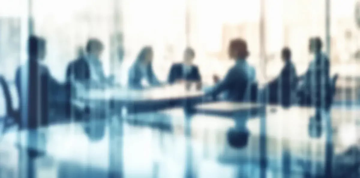A blurred view of a meeting in a conference room behind glass. 