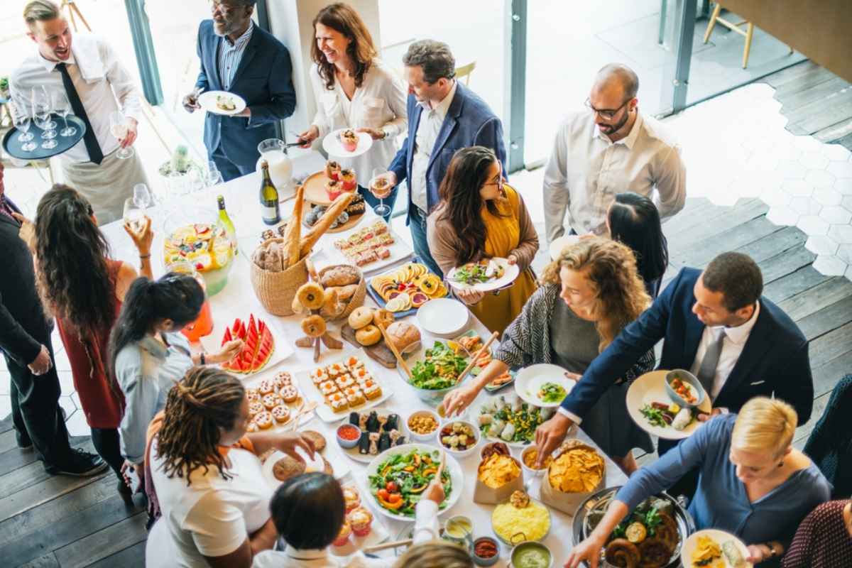 A top-down view of a large buffet table, with people in business casual clothes on either side.