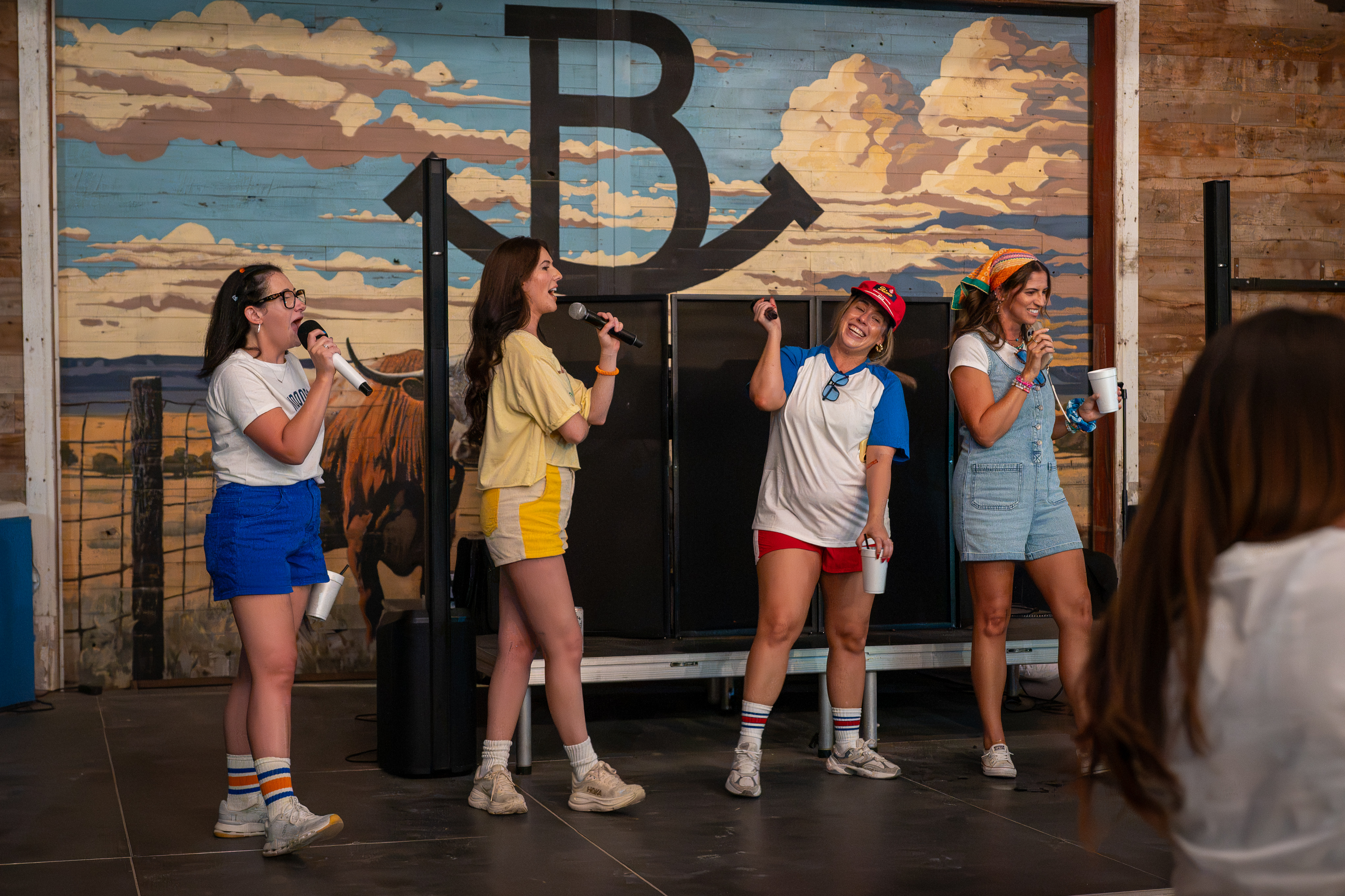 A group of Imprint Event Group employees doing karaoke on a stage at Rocker B Ranch